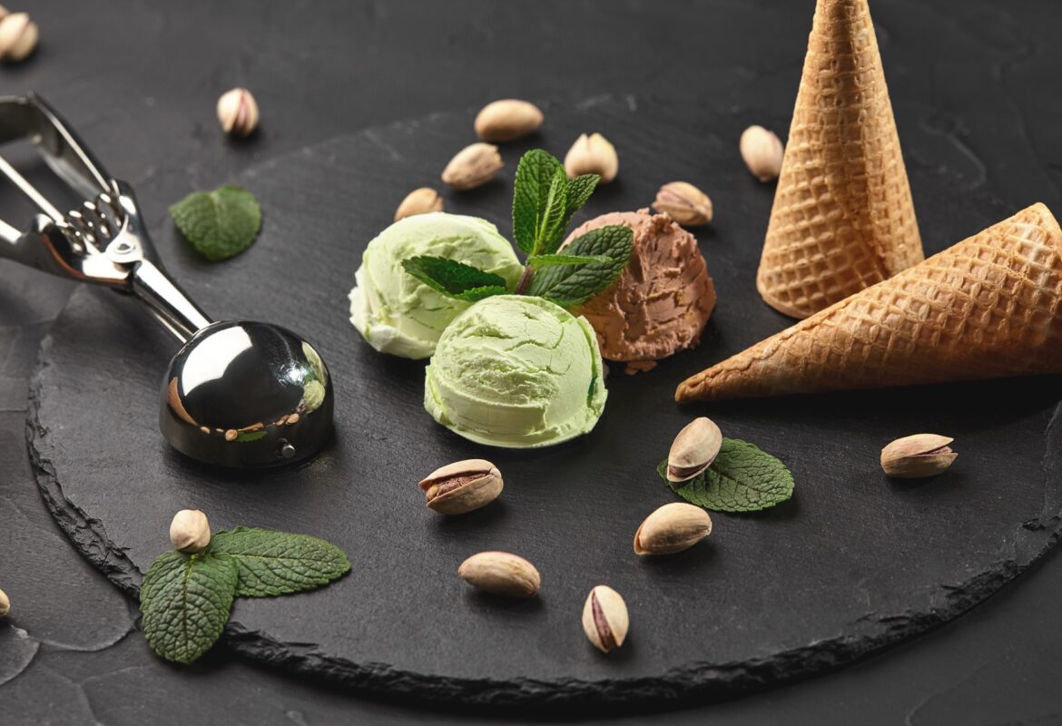 Gourmet chocolate and pistachio ice cream served on a stone slate over a black background.
